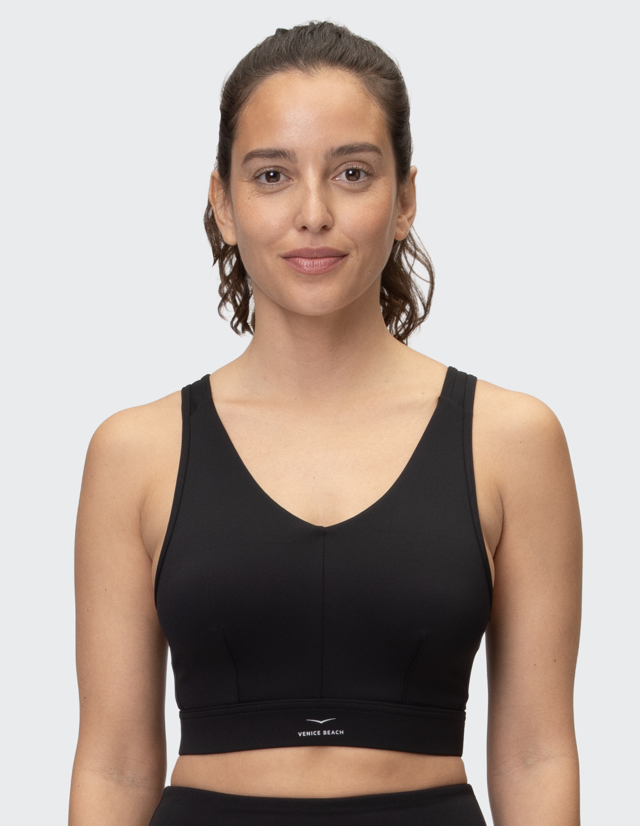 Frau trägt ein schwarzes Venice Beach Abigail-Sportoberteil für lässige Fitness und Faulenzen.