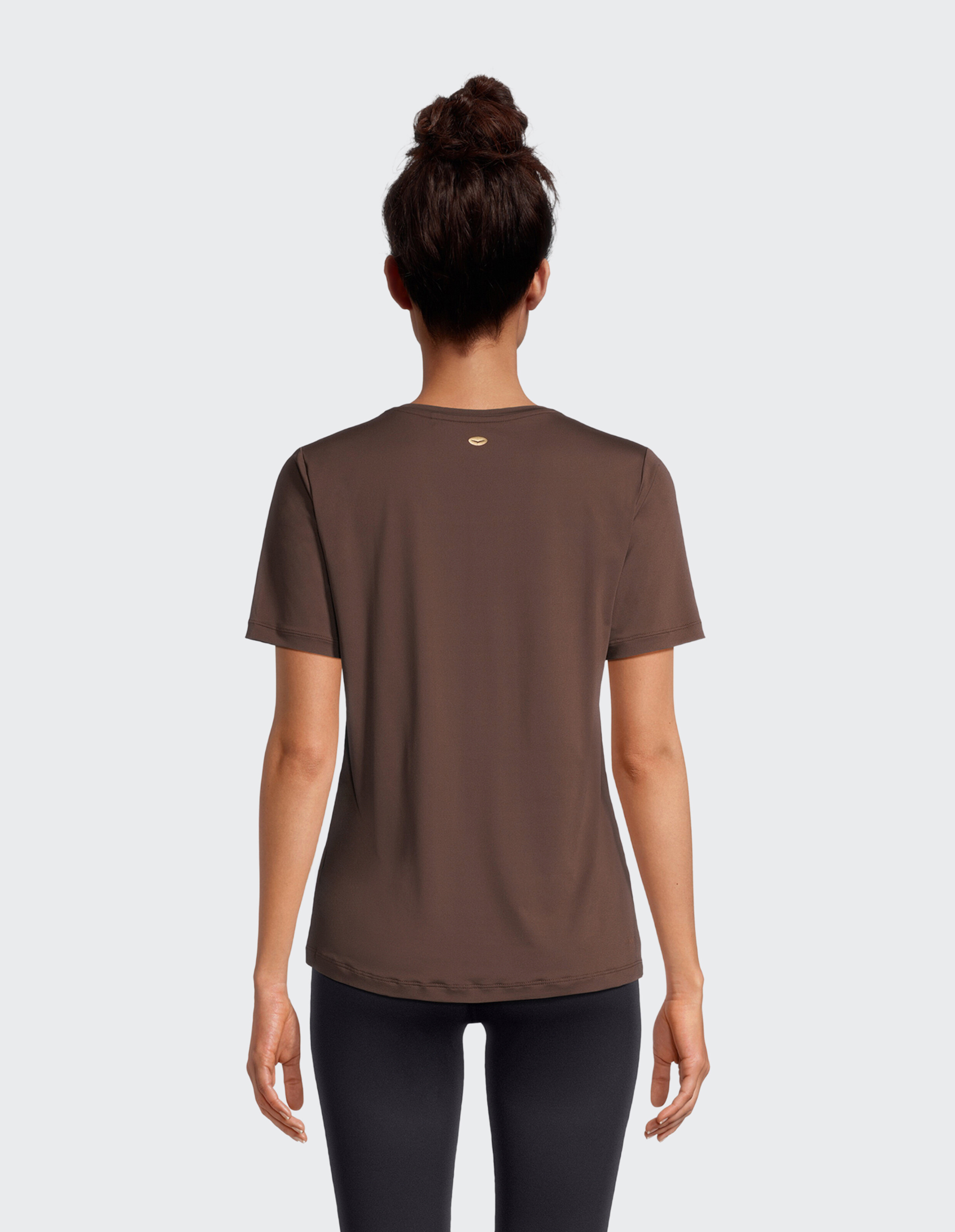 Rückansicht einer Frau, die ein gemütliches braunes Freizeit-T-Shirt mit kleinem Logo-Detail trägt.