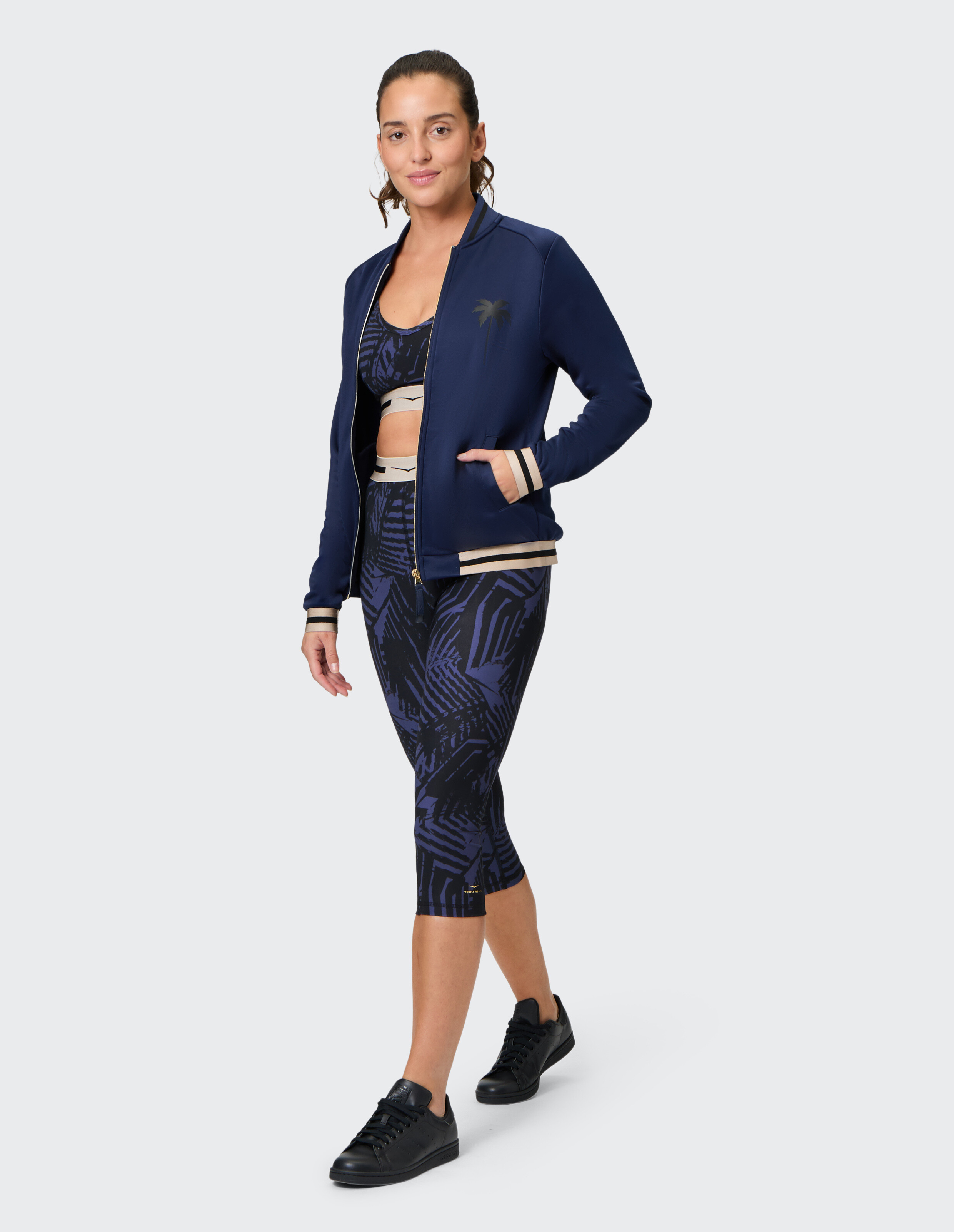 Frau in marineblauer Bomberjacke und gemusterten Leggings, perfekt für Freizeitkleidung.