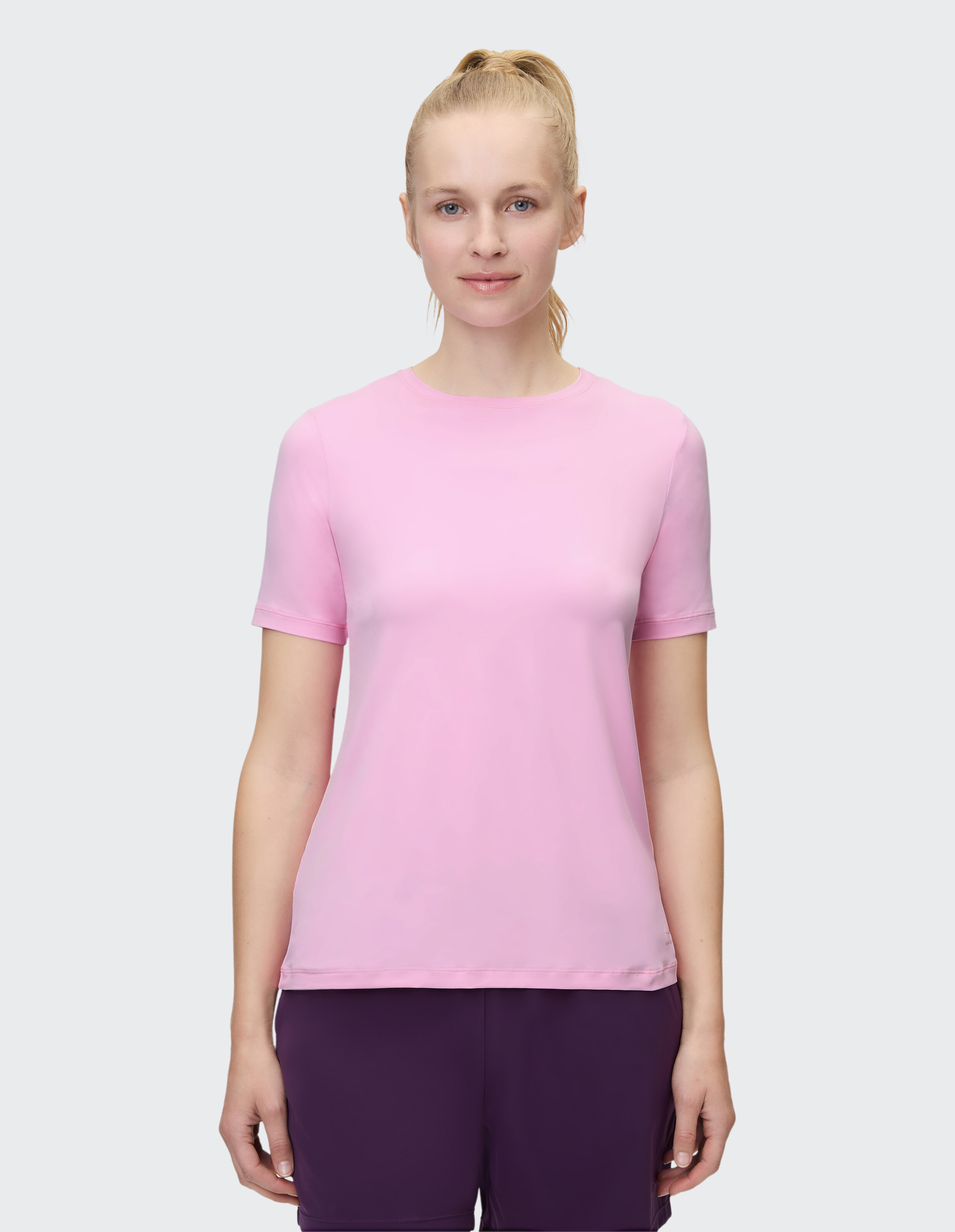 Frau trägt ein hellrosa Kurzarm-T-Shirt, perfekt für Freizeitkleidung.