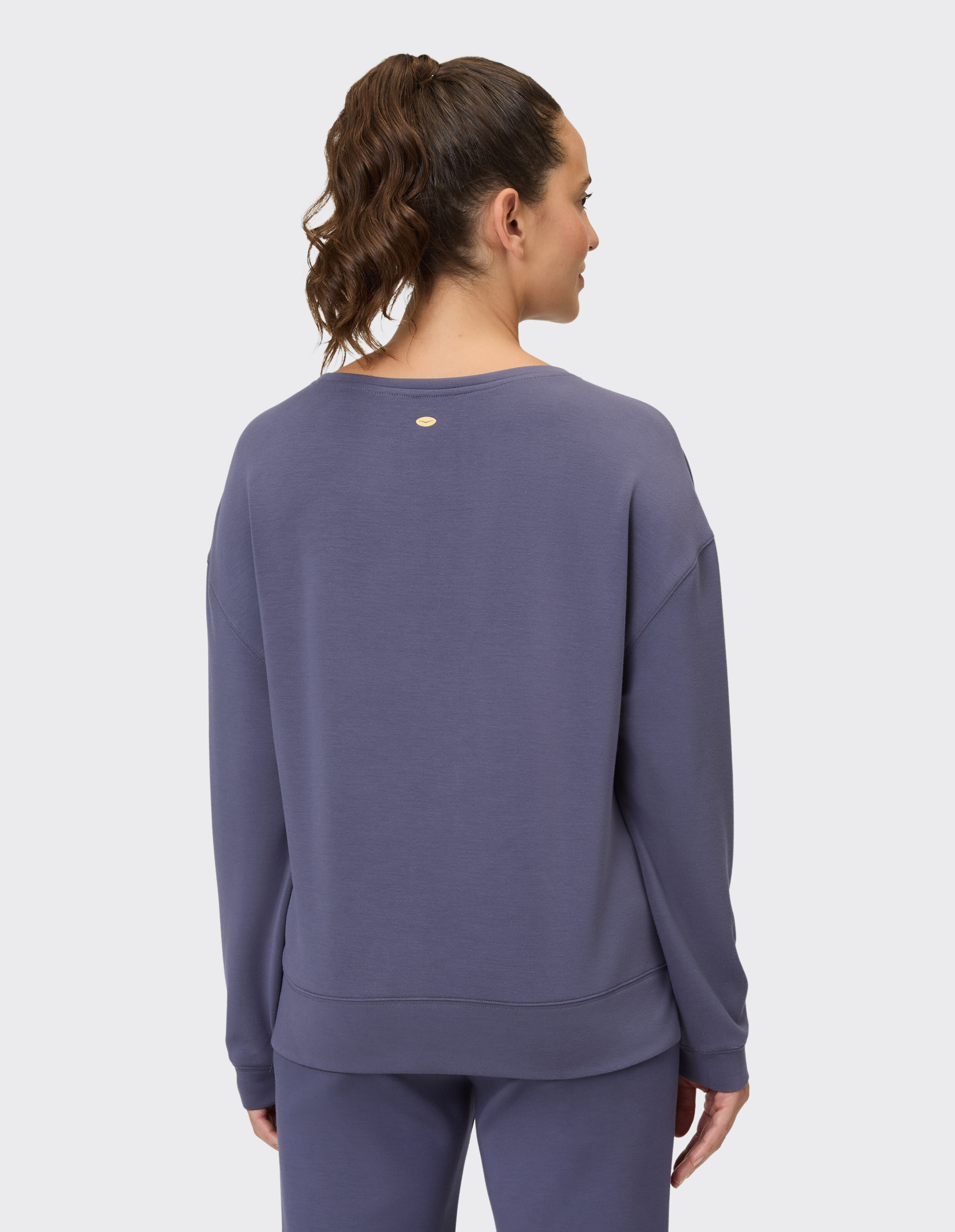 Rückansicht einer Frau in einem kuscheligen lila Sweatshirt, perfekt für Freizeitkleidung.