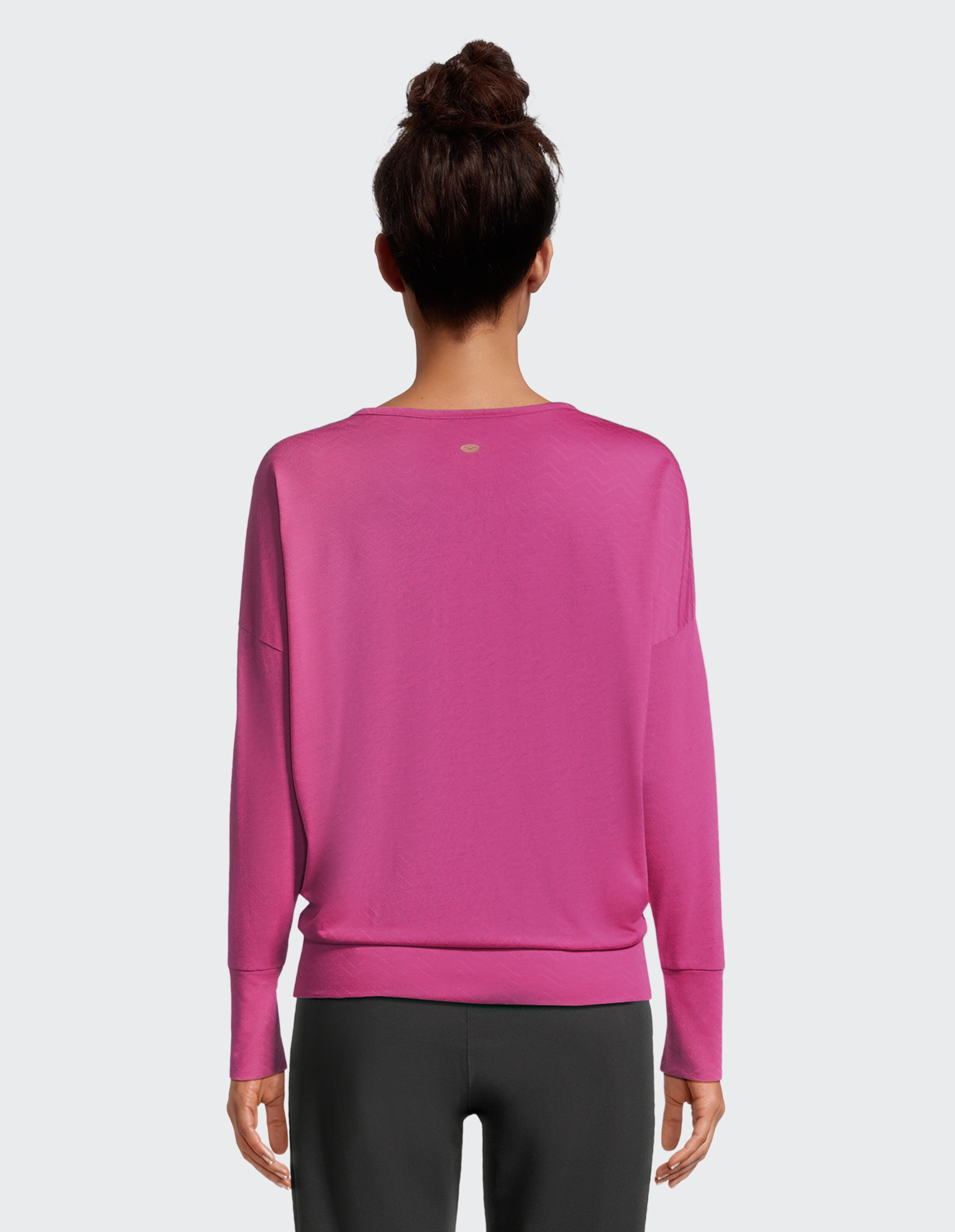 Rückansicht einer Frau, die zum Faulenzen einen gemütlichen rosafarbenen Langarmpullover trägt.