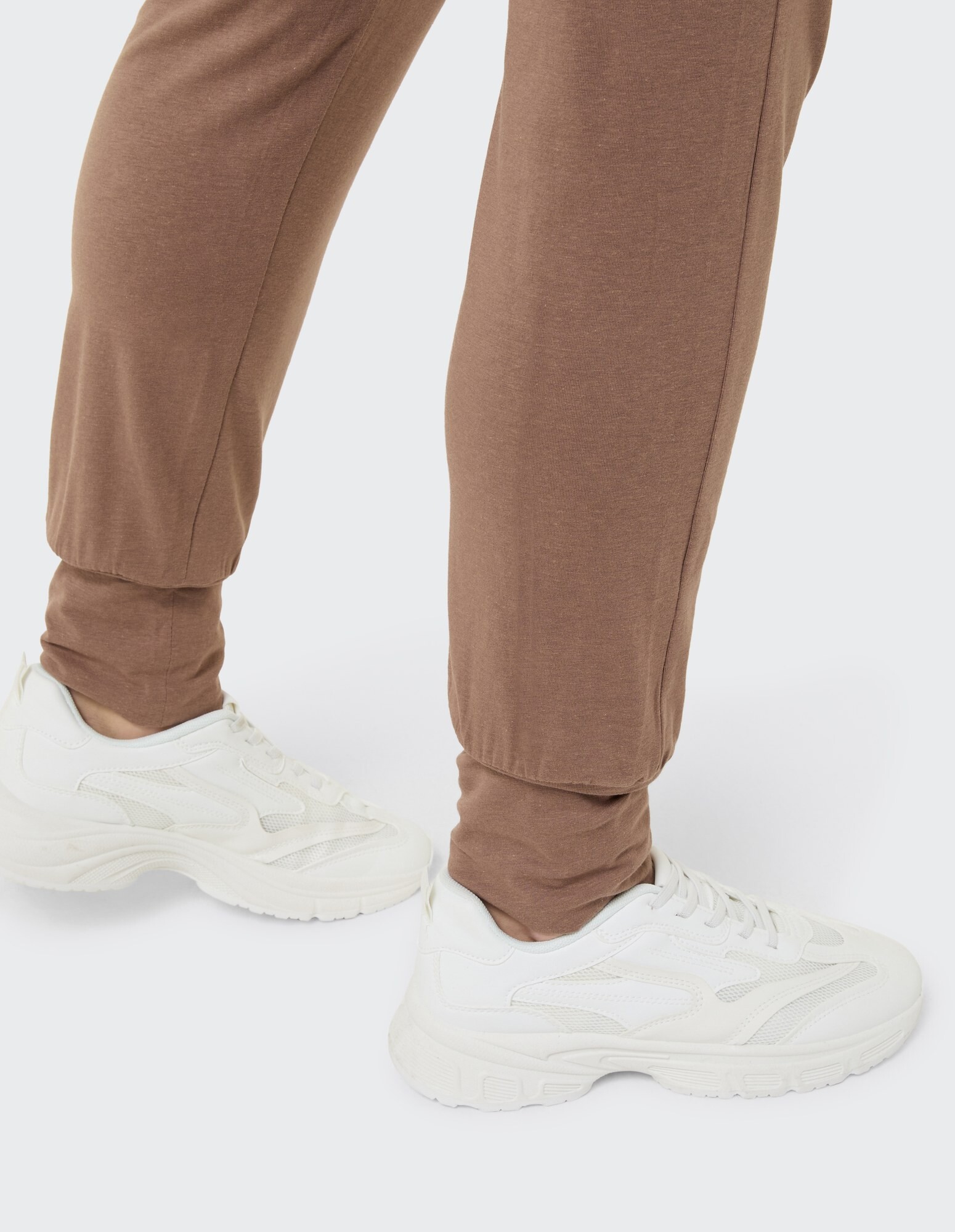 Lässige braune Jogginghose gepaart mit weißen Sneakers, perfekt für entspannte Ausflüge.
