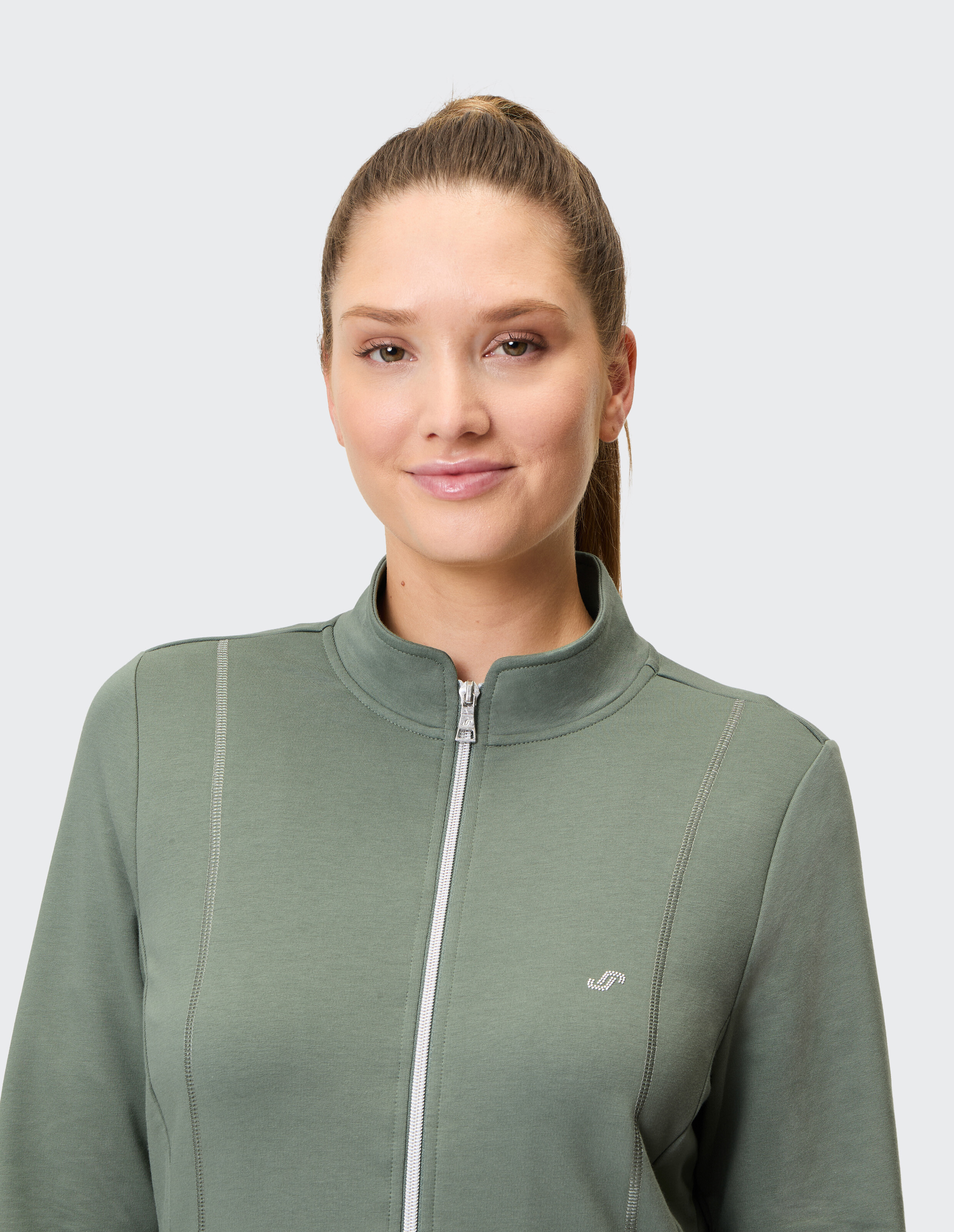 Dunkelgrüne Damenjacke mit Reißverschluss und Stehkragen, dezentem Logo auf der Brust und zwei seitlichen Nähten als Design-Elemente.