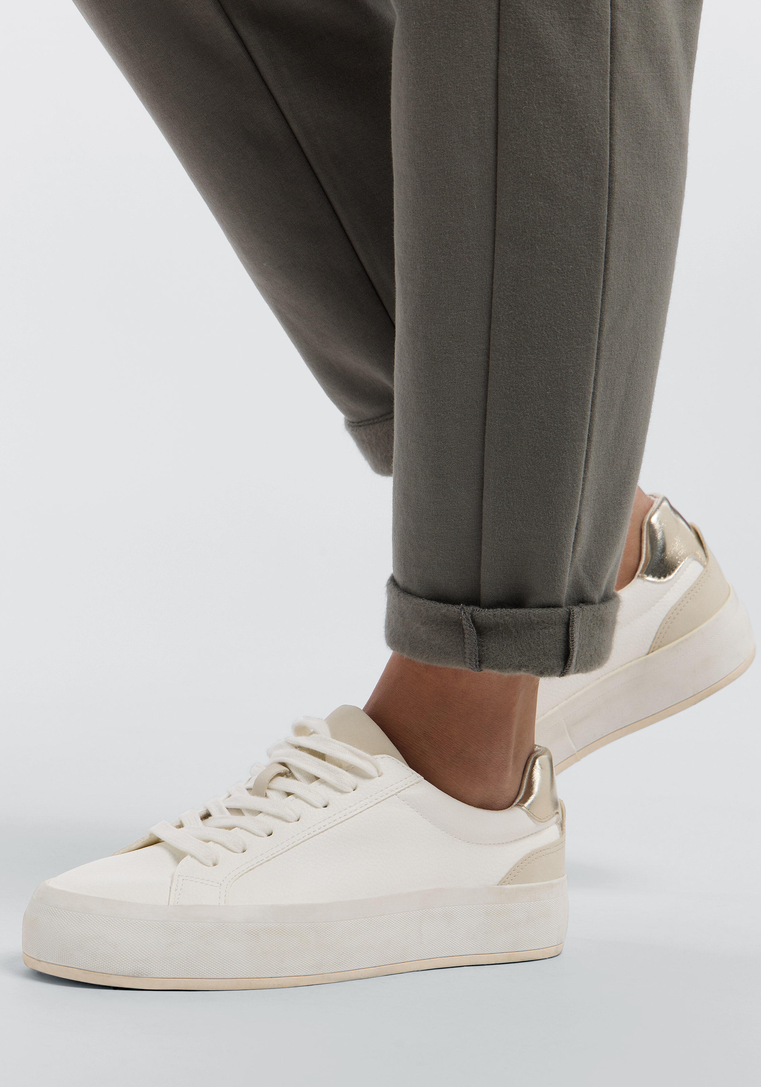 Eine olivgrüne Freizeit-Jogginghose gepaart mit weißen Sneakers für einen bequemen, eleganten Look.