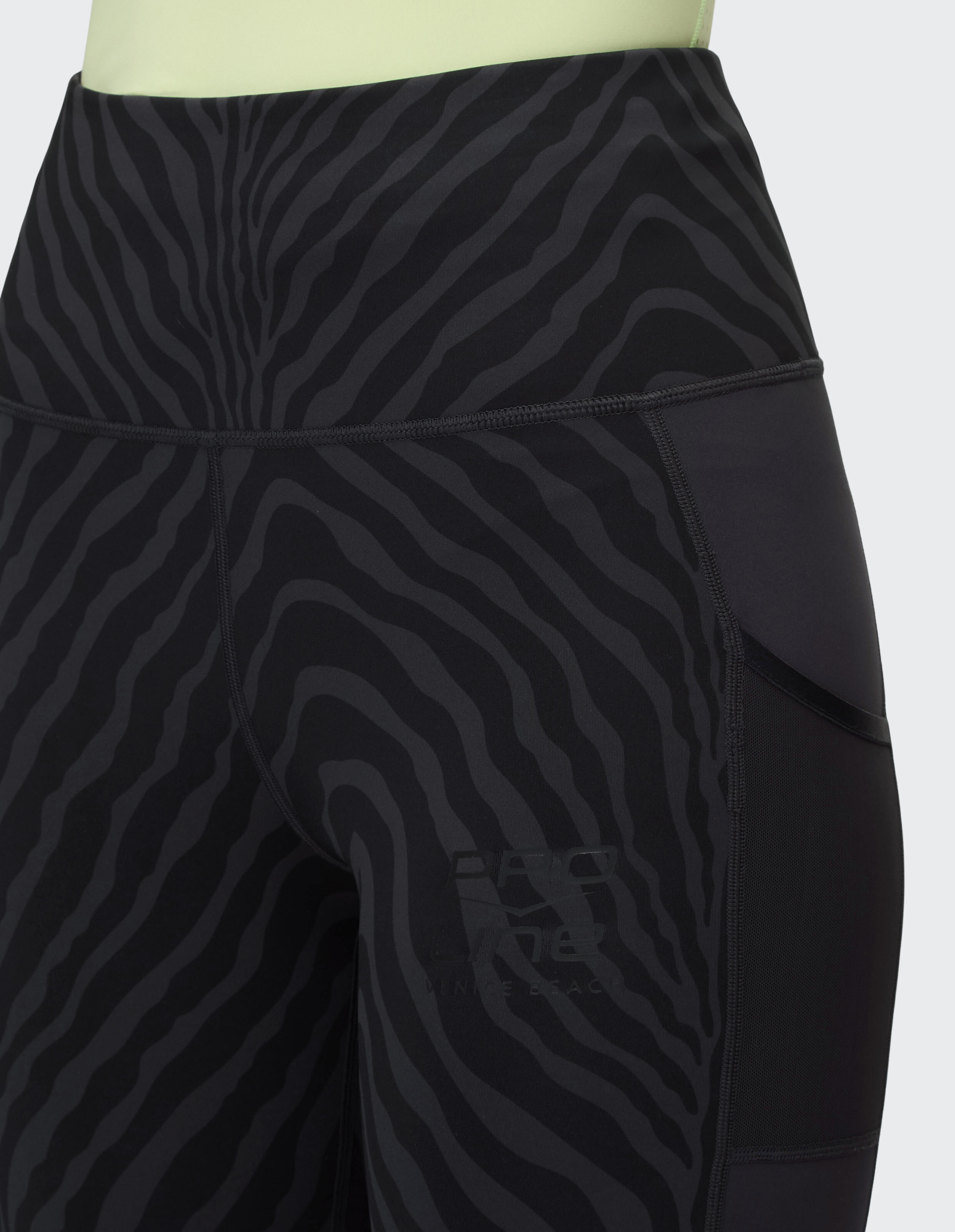 Nahaufnahme einer schwarzen Leggings mit Zebramuster, hohem Bund und Logodetail.