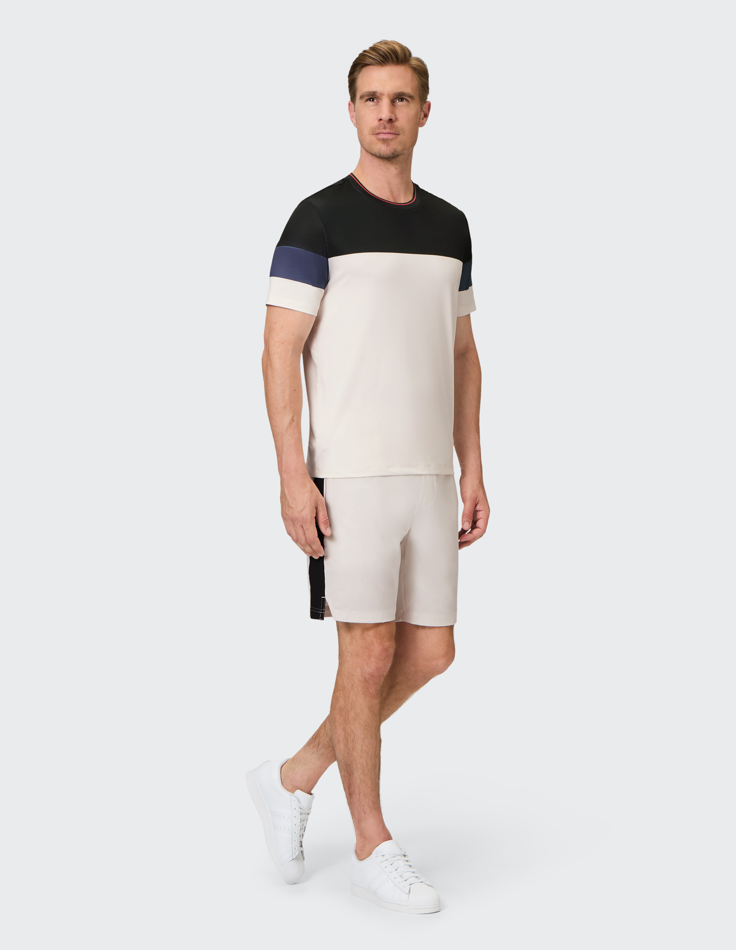 Freizeitkleidung für Herren mit einem T-Shirt und Shorts im Farbblockdesign in neutralen Tönen.
