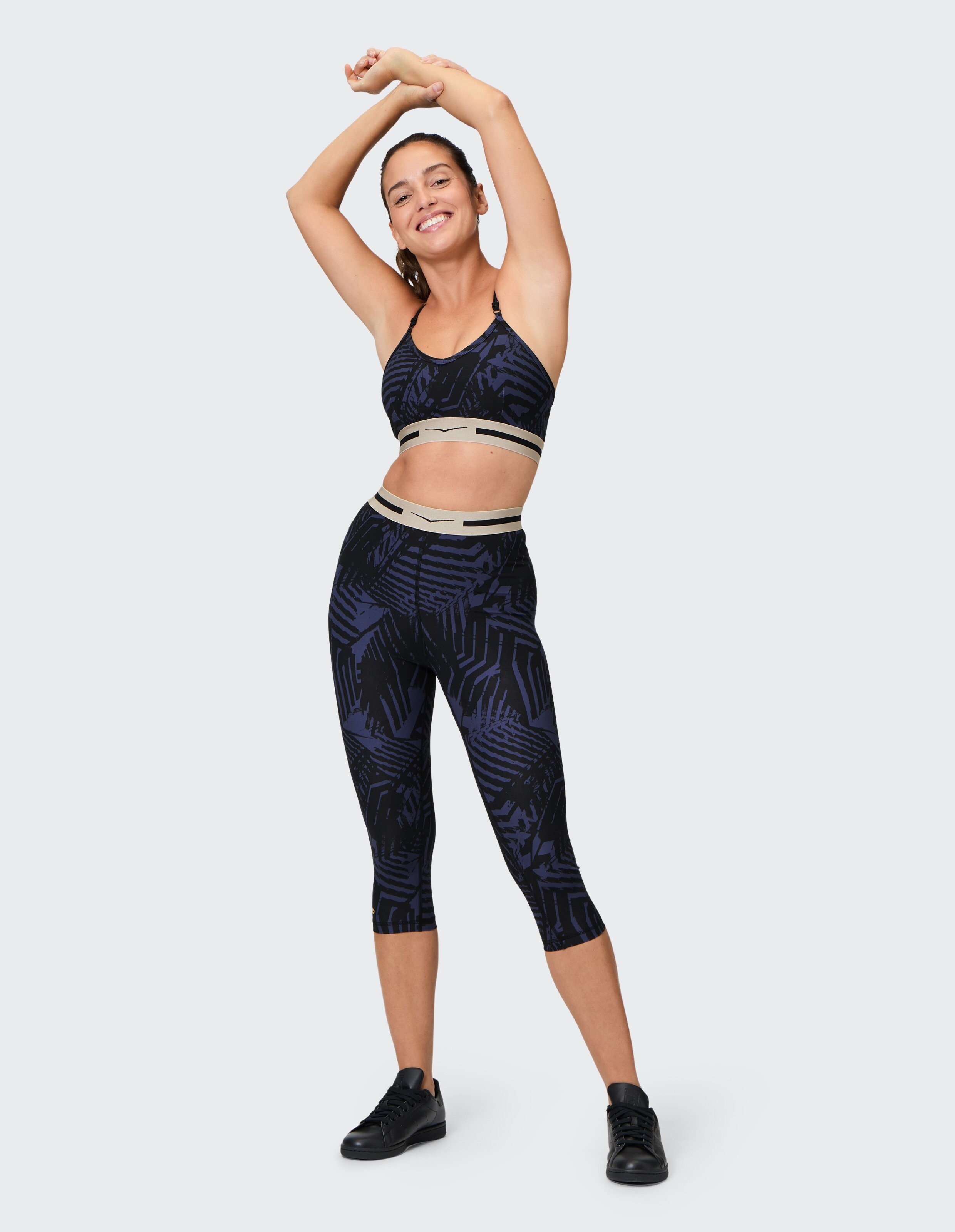 Frau trägt einen gemusterten marineblauen Sport-BH und Capri-Leggings für lässige Aktivkleidung.
