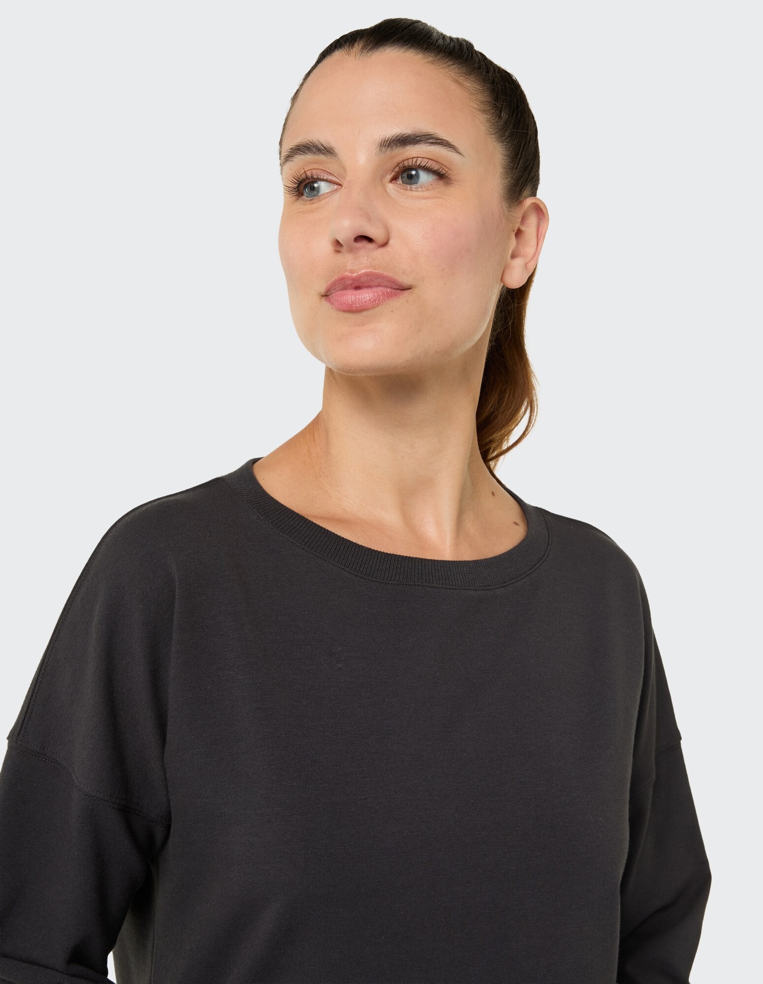 Nahaufnahme einer Frau in einem schwarzen, lässigen Sweatshirt mit lockerer Passform.
