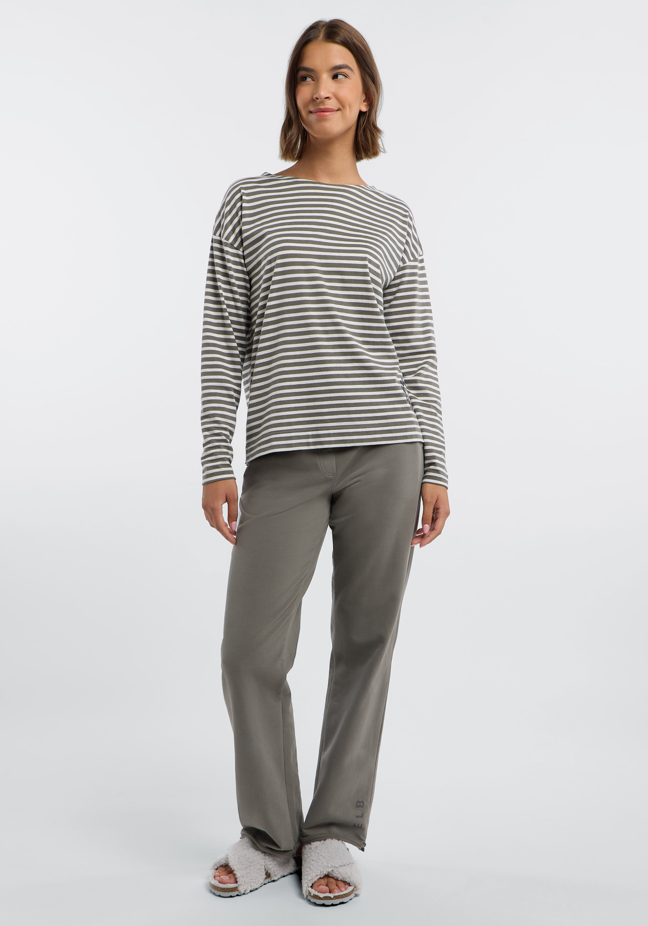 Frau trägt ein gestreiftes Langarmshirt und eine gemütliche graue Loungehose.