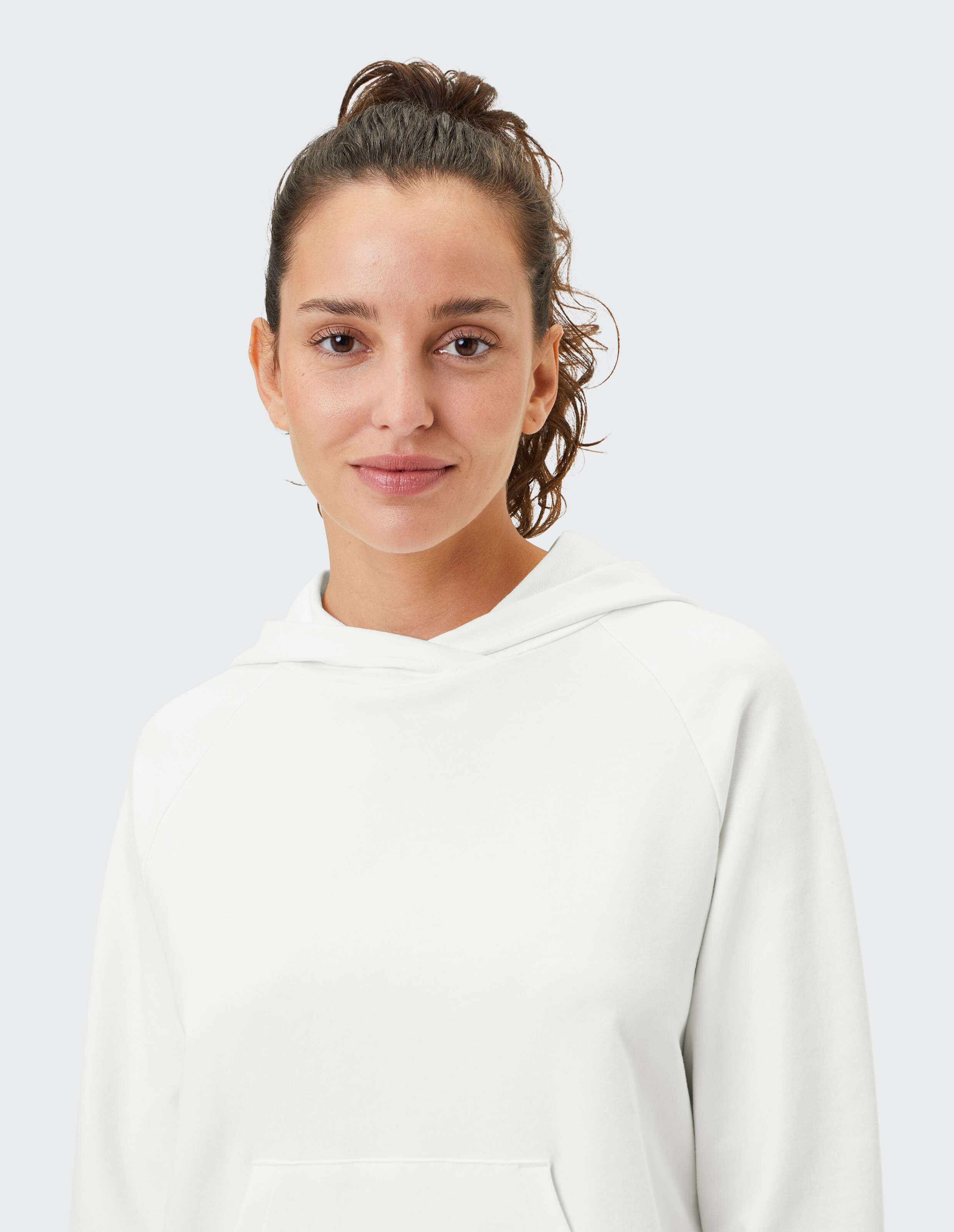 Frau trägt einen gemütlichen weißen, lässigen Kapuzenpullover, perfekt zum Faulenzen oder Reisen.