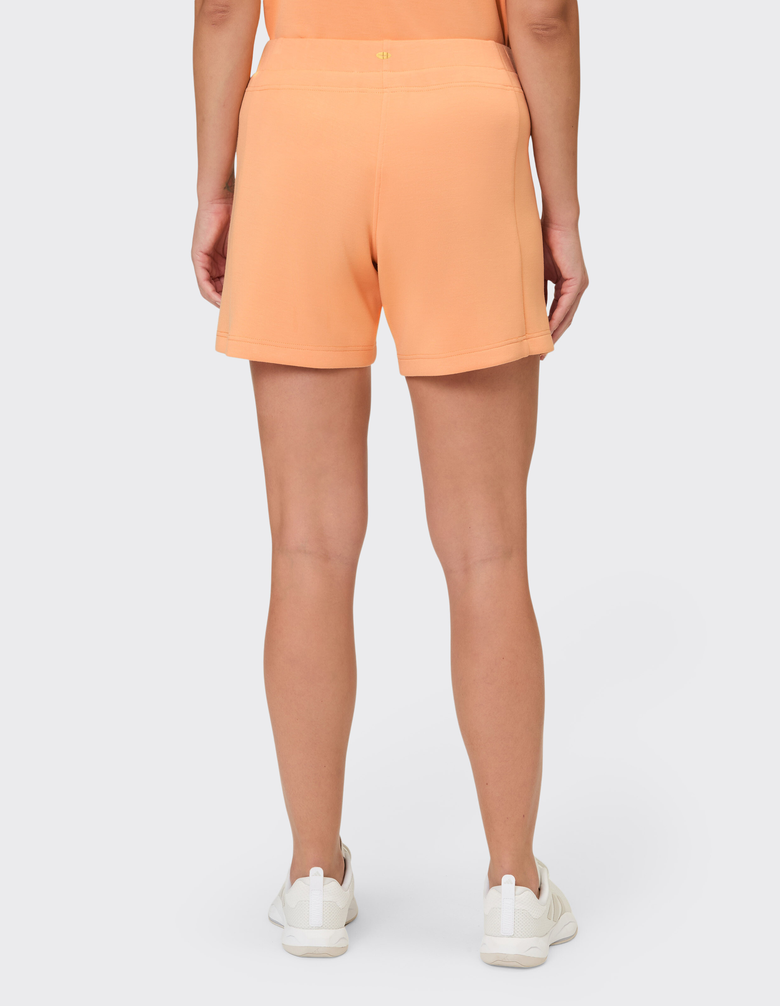 Rückansicht einer Frau in pfirsichfarbenen Shorts, perfekt für lässige Sommerkleidung.