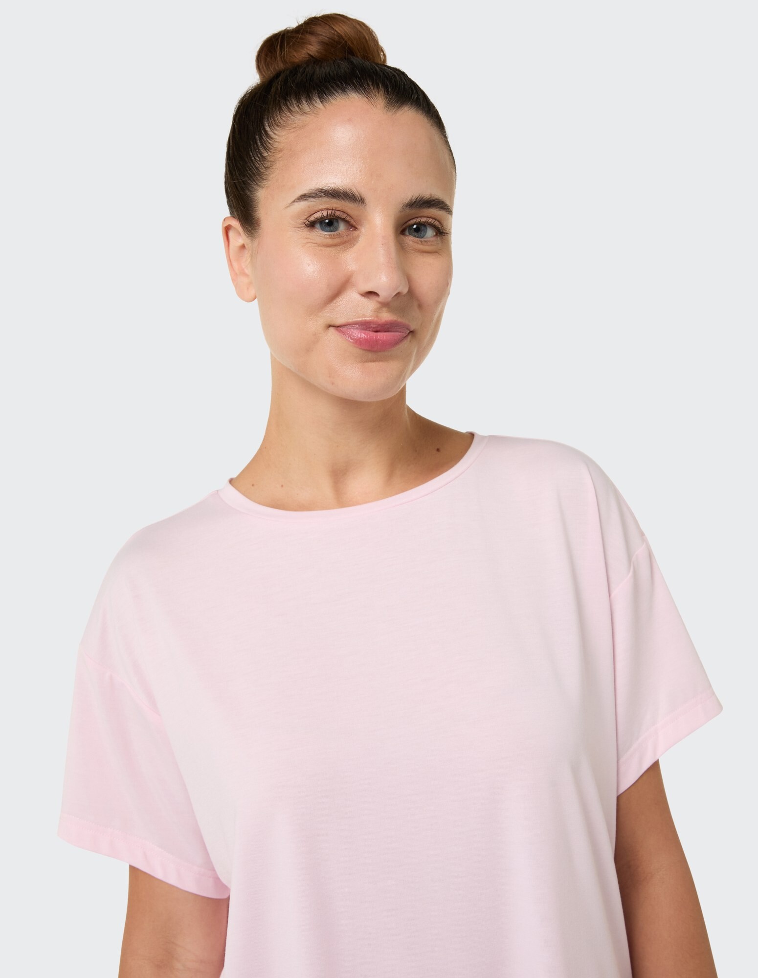 Nahaufnahme einer Frau in einem hellrosa Freizeit-T-Shirt mit entspannter Passform.