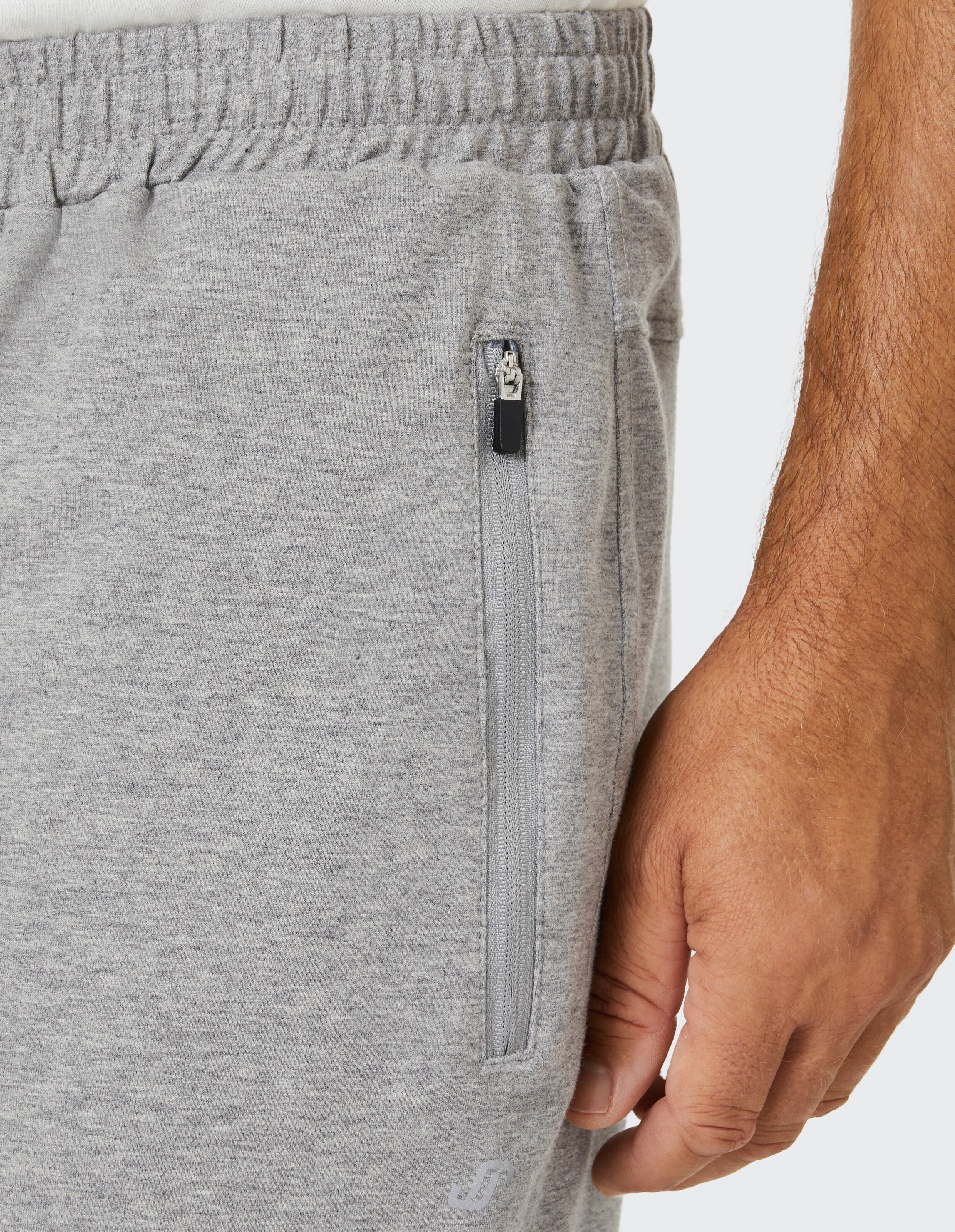 Graue Jogginghose mit elastischem Bund und Reißverschlusstasche, Hand eines Mannes berührt seitlich das weiche Material.