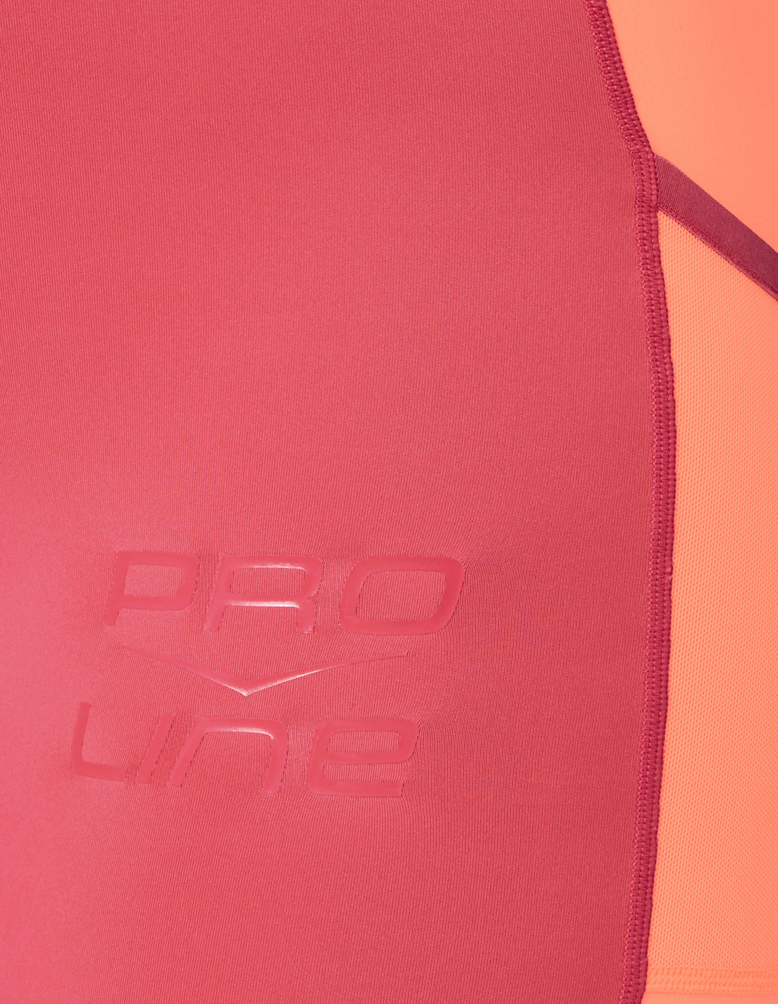 Nahaufnahme eines rosa-orangefarbenen Sportoberteils mit „PRO LINE“-Branding.