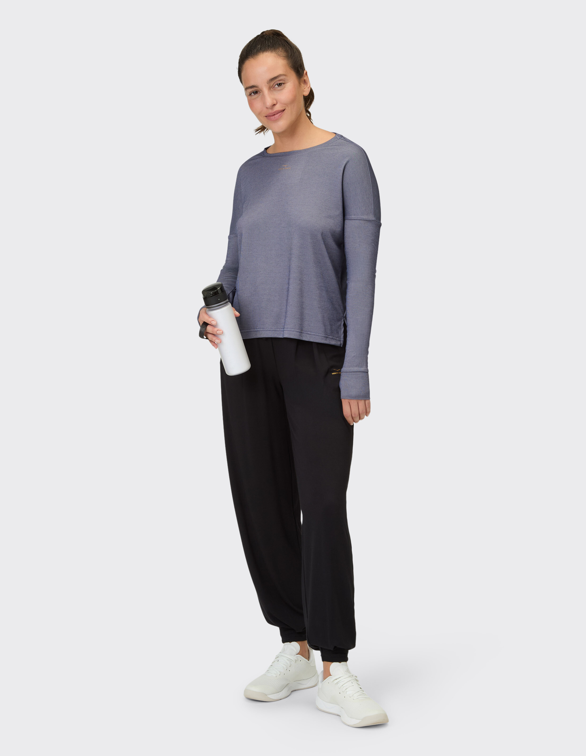 Frau trägt das Venice Beach Langarmshirt Winona in Blau mit schwarzen Jogginghosen.