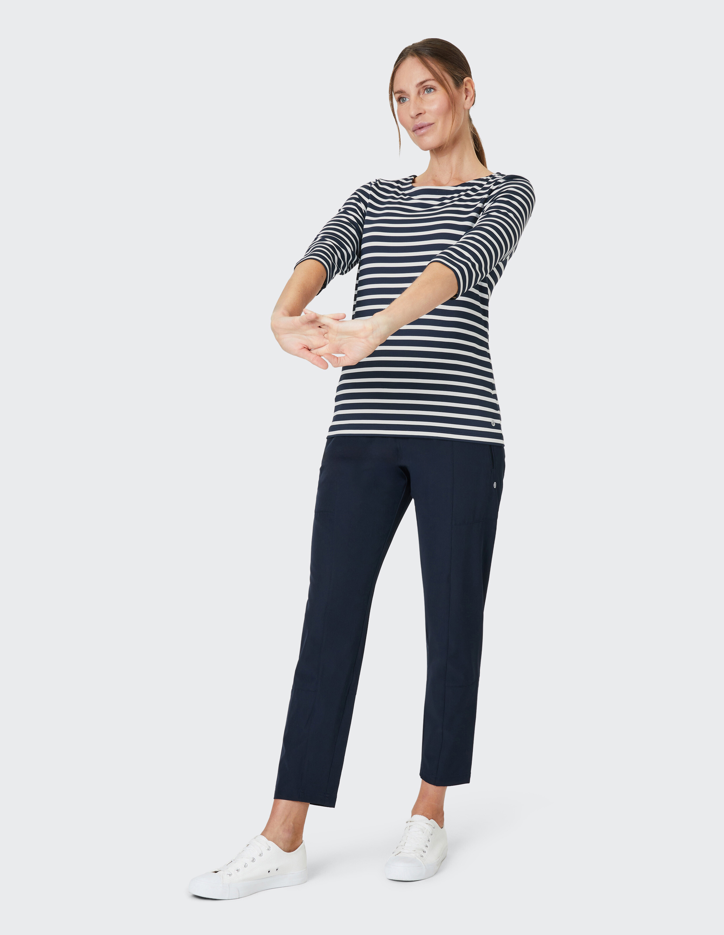 Frau trägt ein dunkelblaues, gestreiftes Langarmhemd und eine dunkelblaue Hose für einen lässigen, bequemen Look.