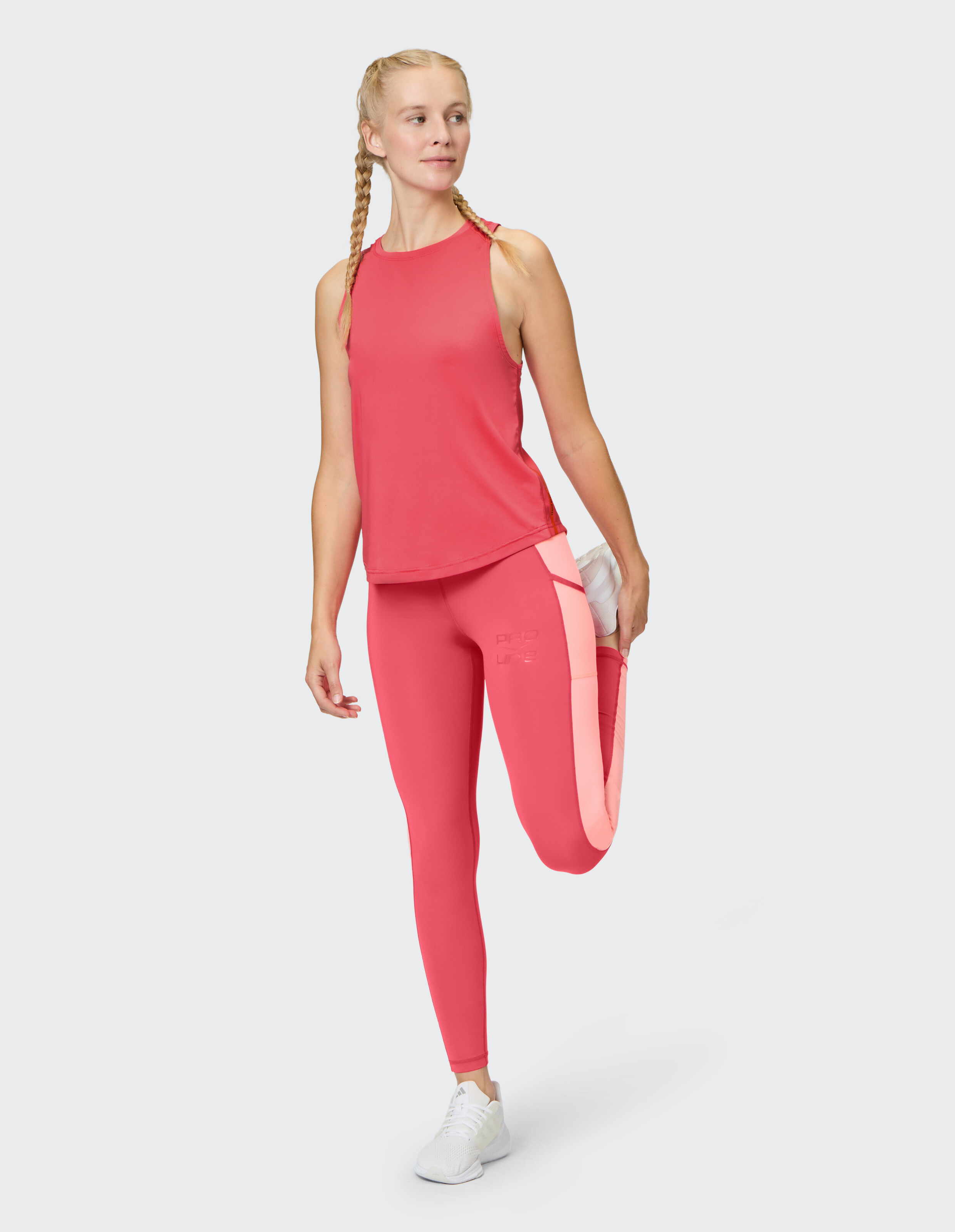 Frau in rosafarbener Sportkleidung zum Stretching, perfekt für lässiges Training oder Faulenzen.