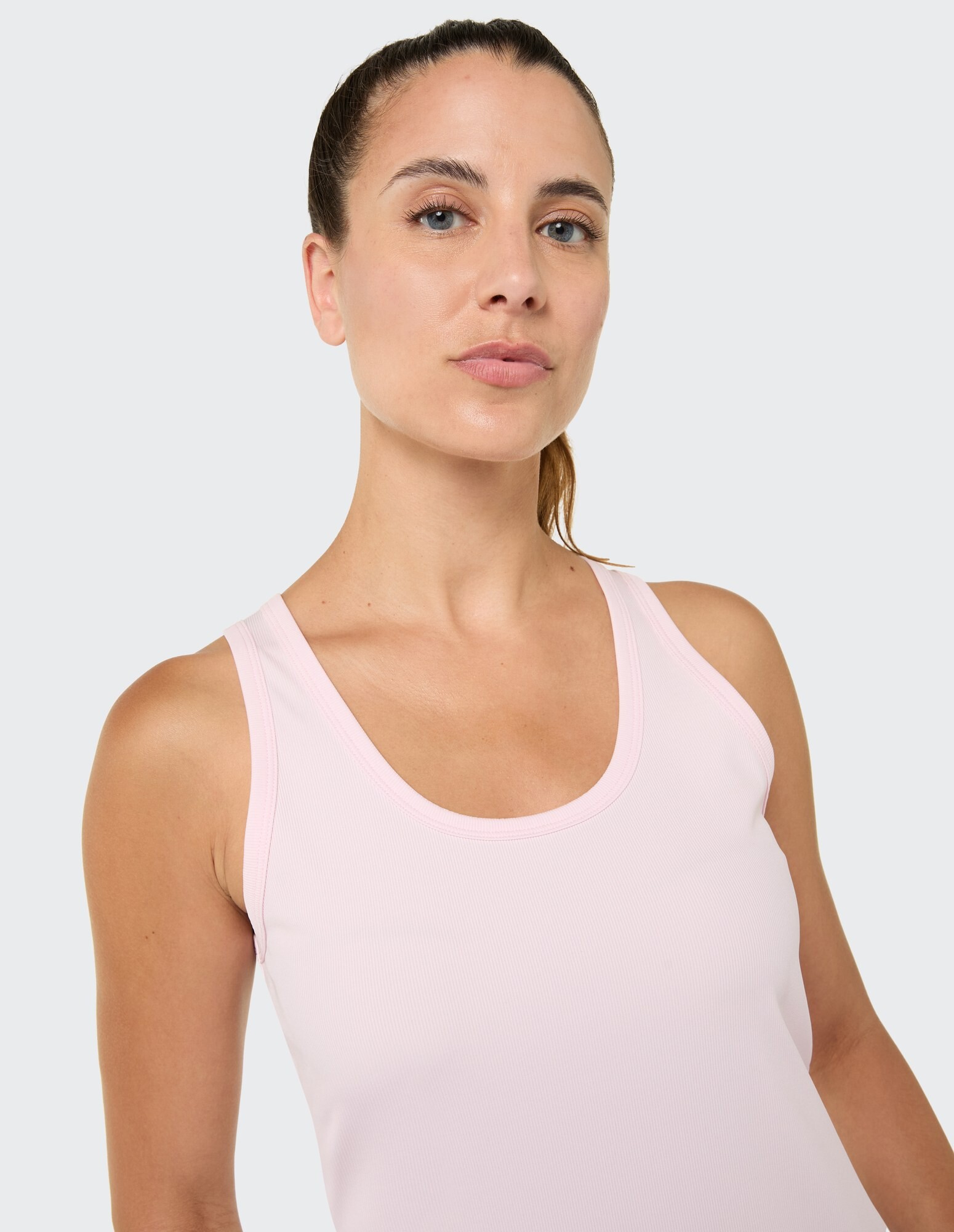 Nahaufnahme einer Frau in einem hellrosa Tanktop, die einen lässigen und bequemen Stil zeigt.
