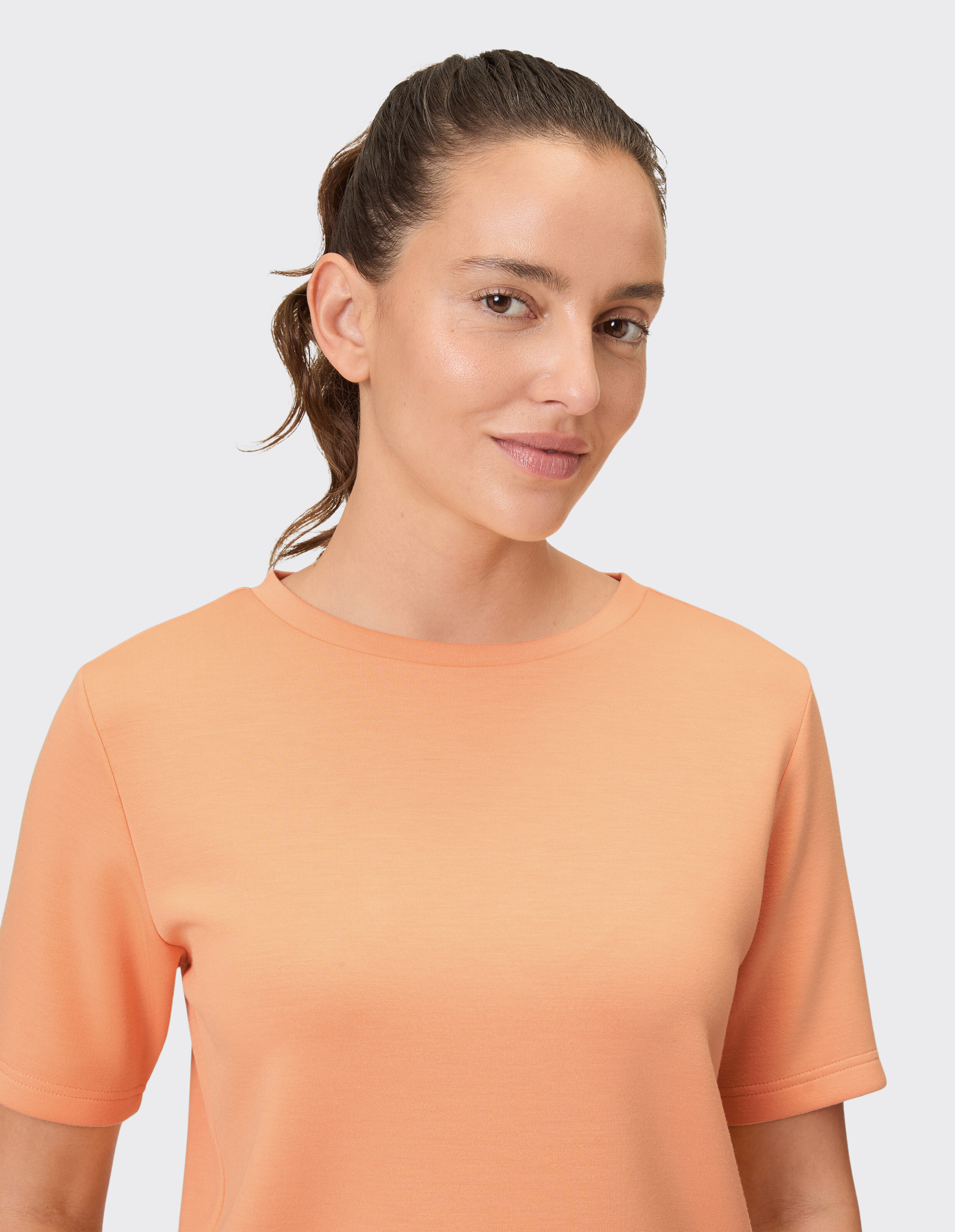 Frau trägt ein gemütliches pfirsichfarbenes Freizeit-T-Shirt für bequemen Alltagsstil.