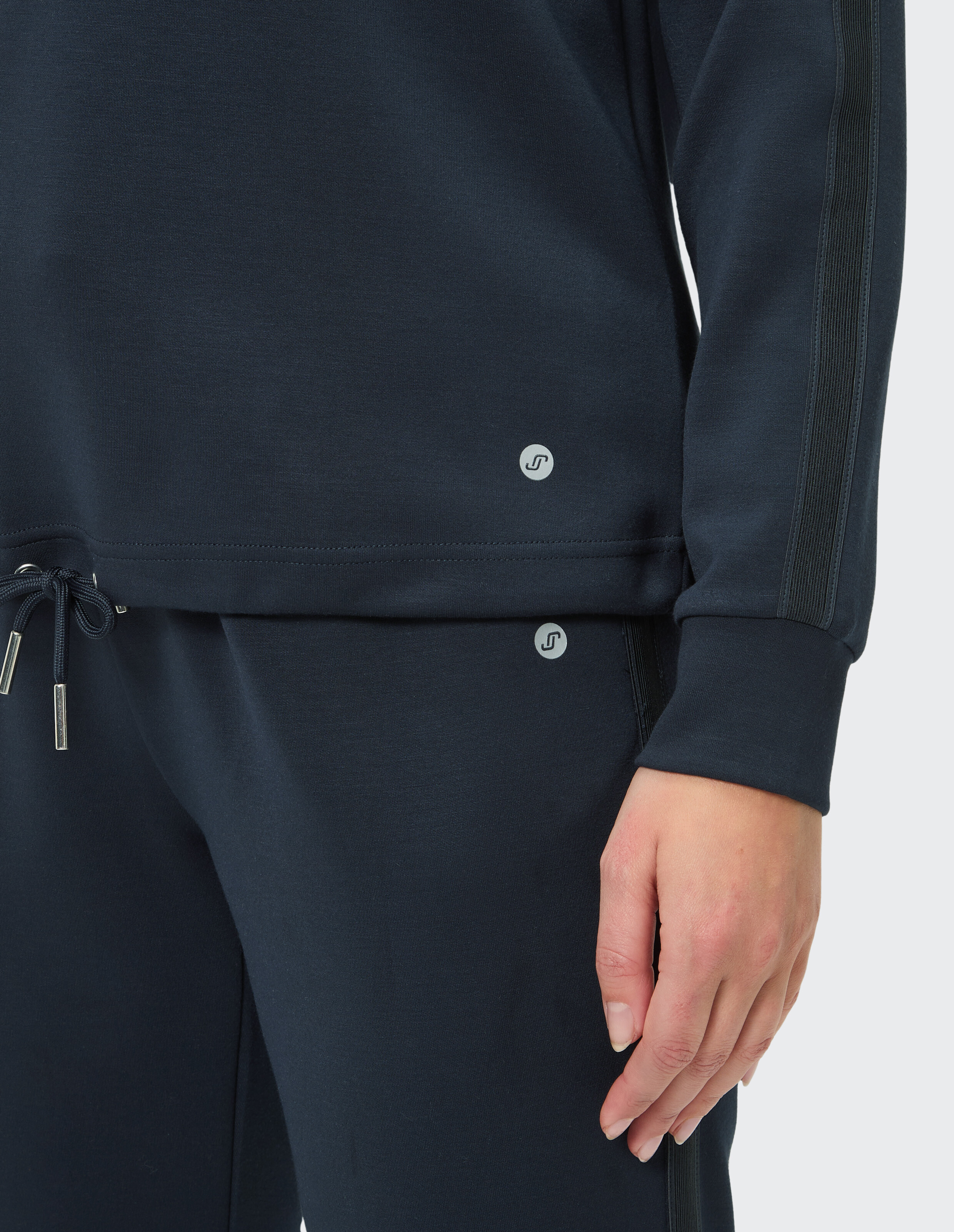 Nahaufnahme eines marineblauen Freizeitoutfits mit weichem Oberteil und passender Hose mit stilvollen Seitenstreifen.