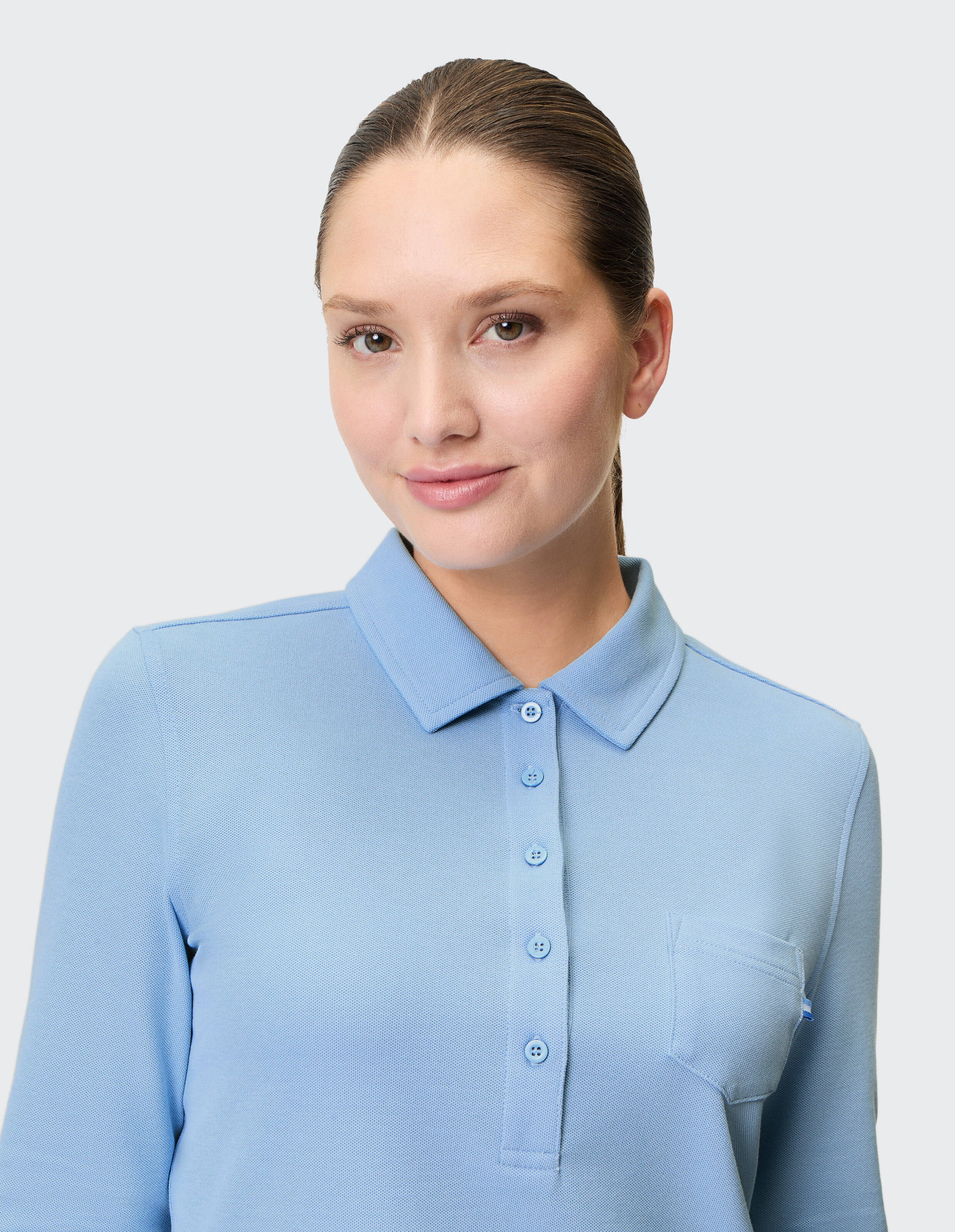 Nahaufnahme einer Frau in einem hellblauen Poloshirt mit Taschendetail.